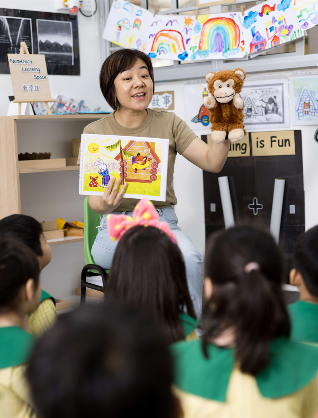 teacher narrating a story to the class using a monkey hand puppet